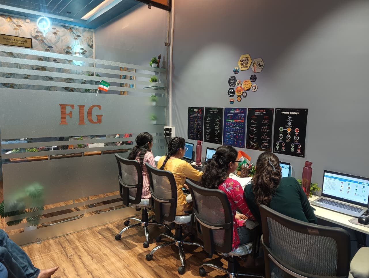 FIG team members working at laptops beside the office glass partition